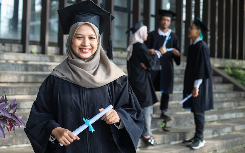 Graduate girl smiling against the background of a group of graduates